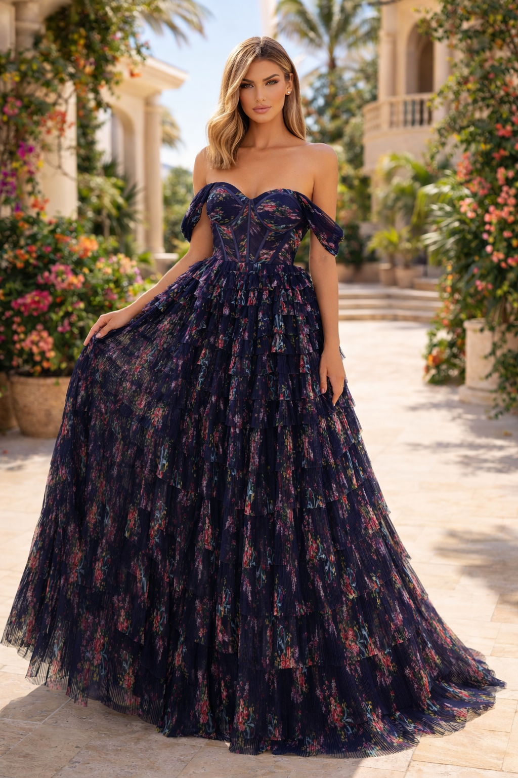 Woman in a dark blue floral off-shoulder gown standing in a garden setting.